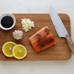 gray knife and orange flesh meat on wooden chopping board